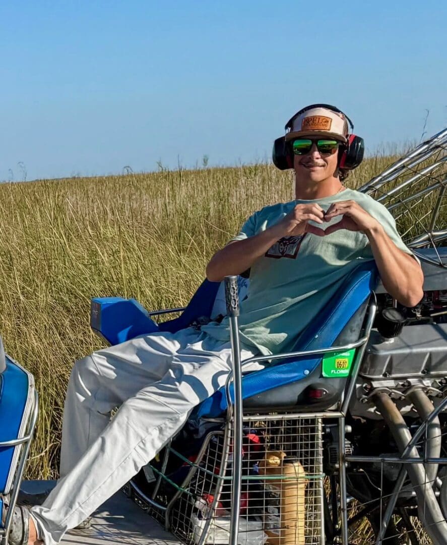 Person on airboat making heart shape hands.