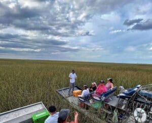 Airboat tour through expansive marshland under clouds.