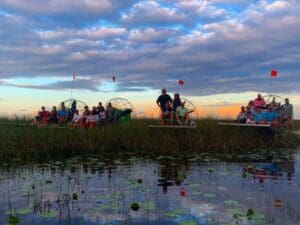 People on airboats in marshy area.