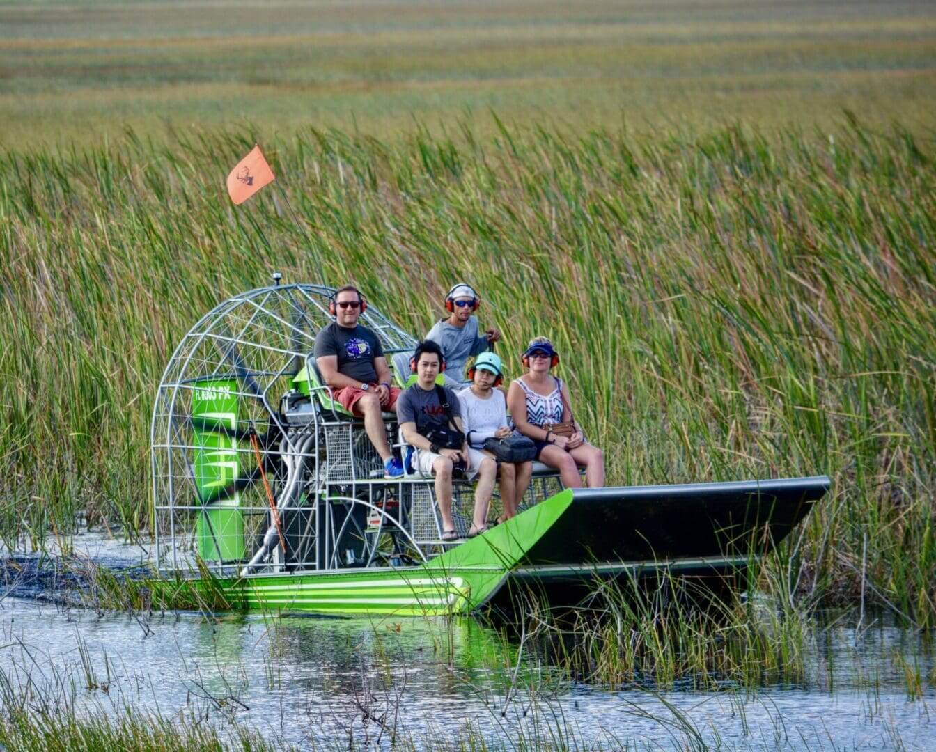 People enjoying an airboat ride through marsh.