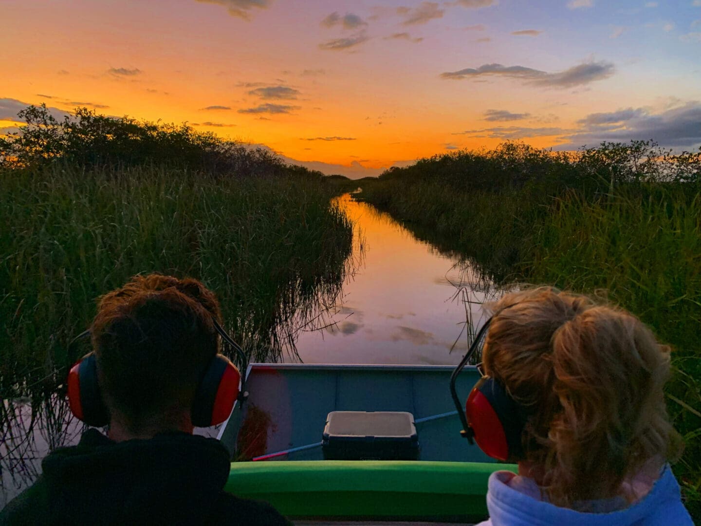 People on boat at sunset in marsh.